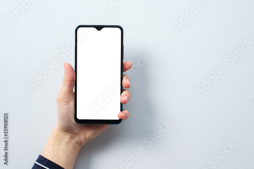 Concept of use of the smartphone. A smartphone with a white blank screen in the hand of a woman.