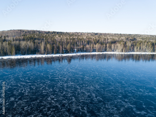 Aerial view on the Onega lake covered with thin ice and the forest, northwest of Russia