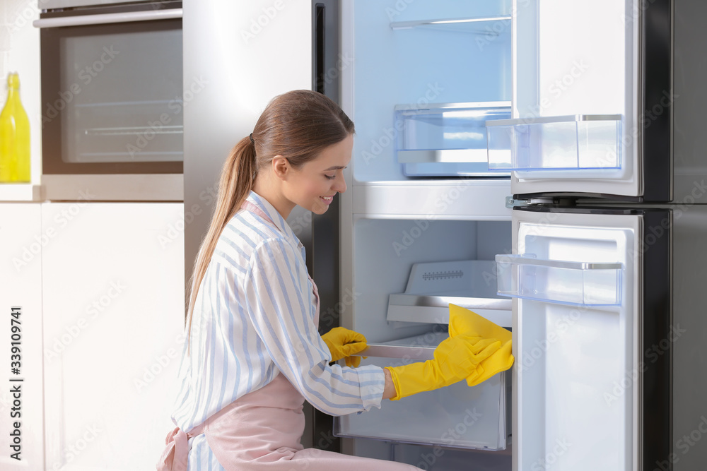 Woman in rubber gloves cleaning refrigerator at home Woman in rubber gloves cleaning refrigerator at home