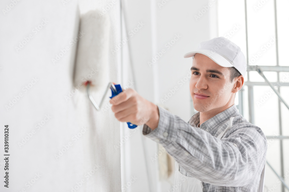 Friendly young male painter painting a wall Friendly young male painter painting a wall