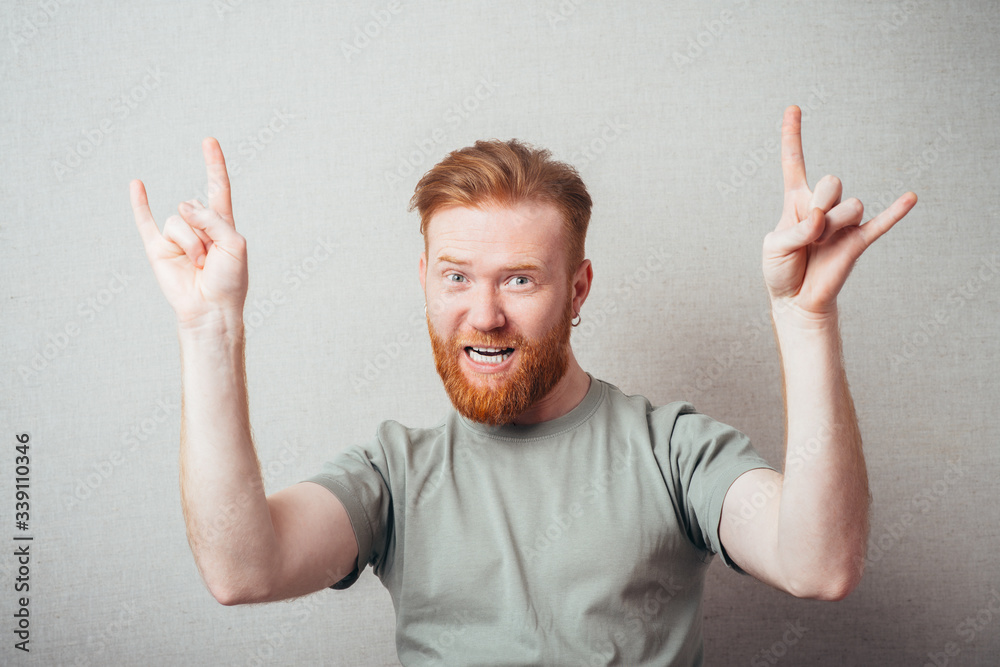 Attractive Young red bearded Man showing gesture hands of rock and roll Attractive Young red bearded Man showing gesture hands of rock and roll