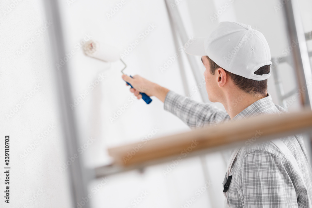 Young painter painting a white wall Young painter painting a white wall