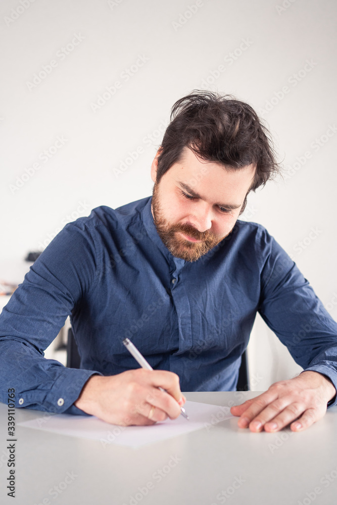 man writes on a piece of paper at the table man writes on a piece of paper at the table