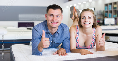 Young happy family couple choosing mattress