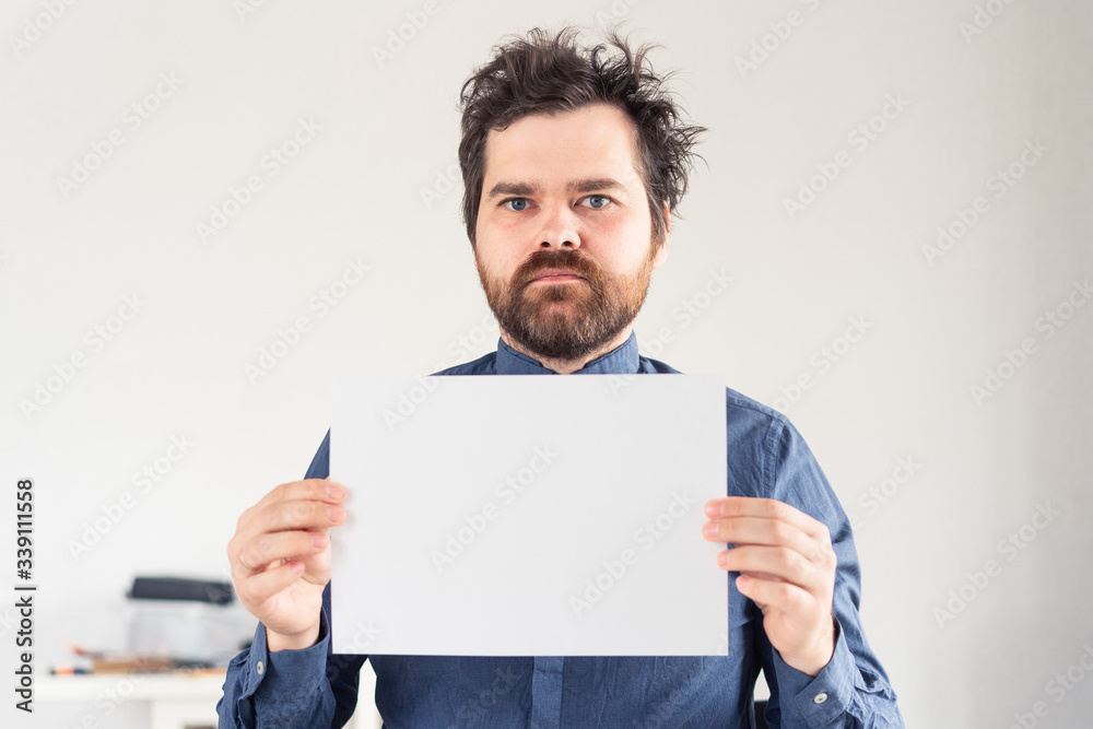 man with a white sheet of paper in his hands in a shirt on a light background man with a white sheet of paper in his hands in a shirt on a light background