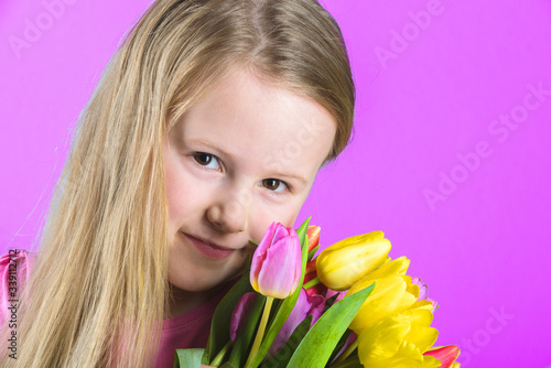 Smiling blond girl with a bouquet of tulips.