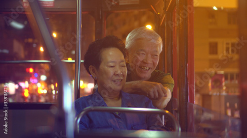 Photography Asian elder couple have fun travel through Hong Kong city tram at night light
