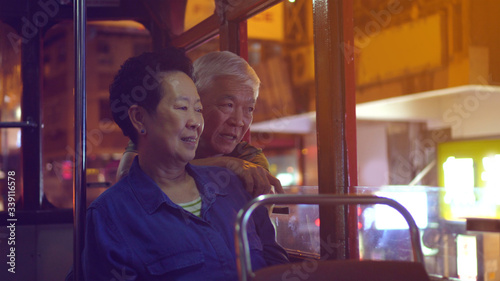Photography Asian elder couple have fun travel through Hong Kong city tram at night