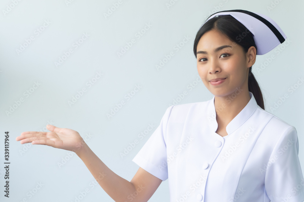 portrait of asian woman nurse pointing to isolated blank space; confident and professional female nurse or medical worker pointing her hand sideway to copy space