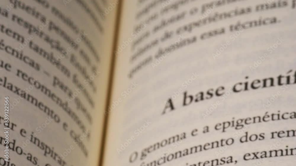 Book in portuguese page and white finger pointing a scientific sentences, closeup Book in portuguese page and white finger pointing a scientific sentences, closeup
