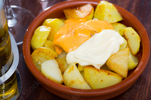 Spanish cuisine. Delicious deep fried potatoes (Patatas bravas) with two sauces in clayware