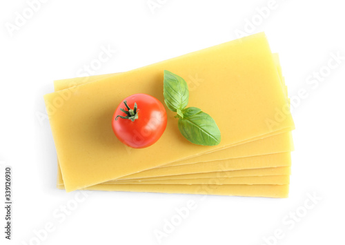Uncooked lasagna sheets, tomato and basil on white background, top view