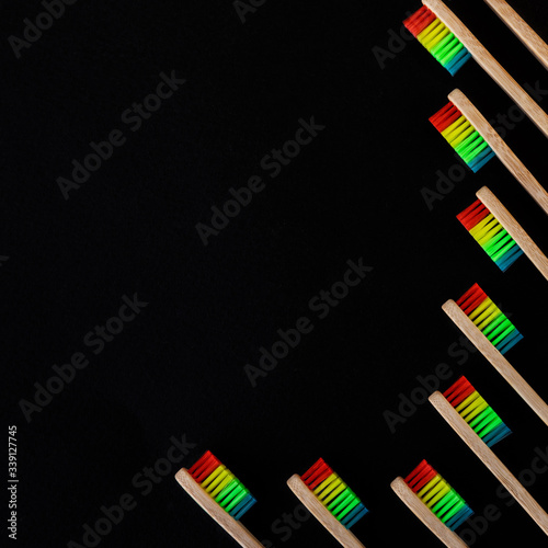 Group of rainbow eco bamboo toothbrushes, on black background. Top view, copy space. Natural organic product for oral hygiene. Dental zero waste and no plastic concept. Safe for the earth. .
