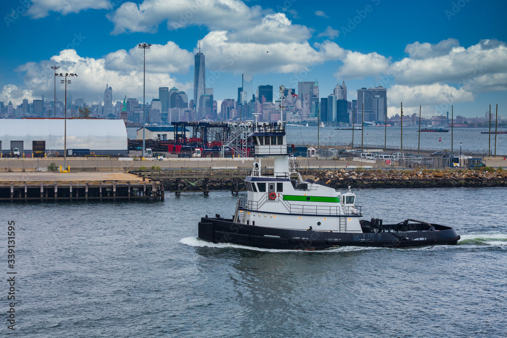 Green and white tugboat from Brooklyn with city in background