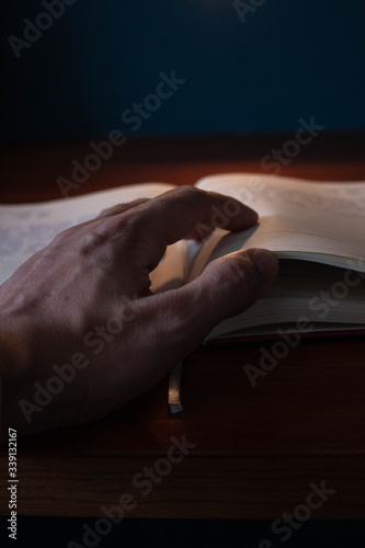 Diario en oficina de casa pasando paginas con la mano indicando los meses actuales en mesa de madera y pared azul 