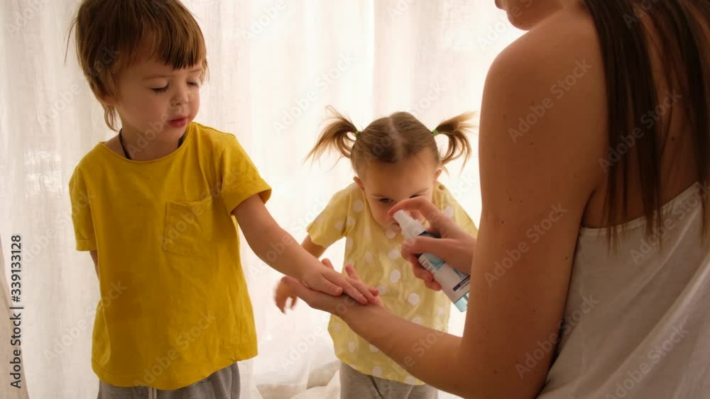 Parent sprays children's hands with a sanitizer house on a white background Parent sprays children's hands with a sanitizer house on a white background