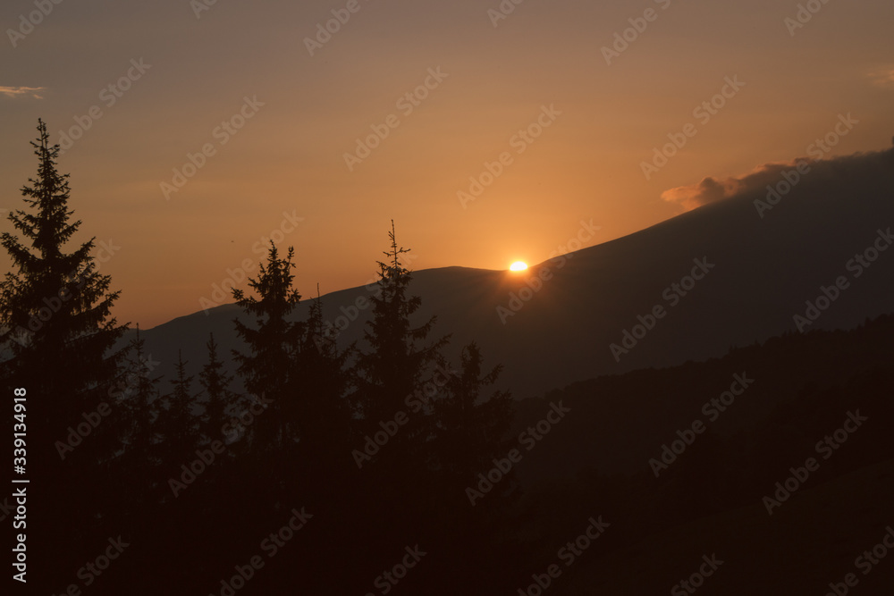 Naklejka premium wonderful orange sunset in mountains during the hike