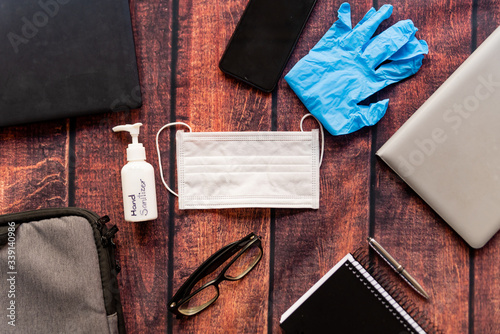 remote work kit on wooden office desk with hand sanitizer and face mask, a solution against the spread of corona virus for quarantined employees photo