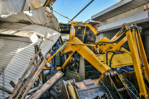 Excavator is stuck between rows of demolished containers at market during reconstruction.