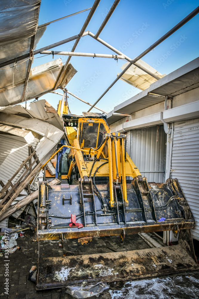 Excavator is stuck between rows of demolished containers at market during reconstruction.