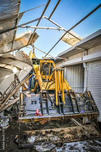 Excavator is stuck between rows of demolished containers at market during reconstruction.