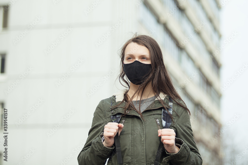 Portrait of a young girl in the ear loop mask, building in the background. Teenager in facial mask