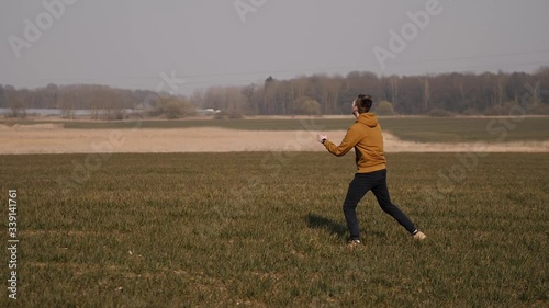 young sports man runs in the field and launches a boomerang into the sky