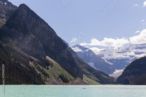 turquoise water lake in the middle of a forest with tall trees and huge mountains  during the summer in Canada