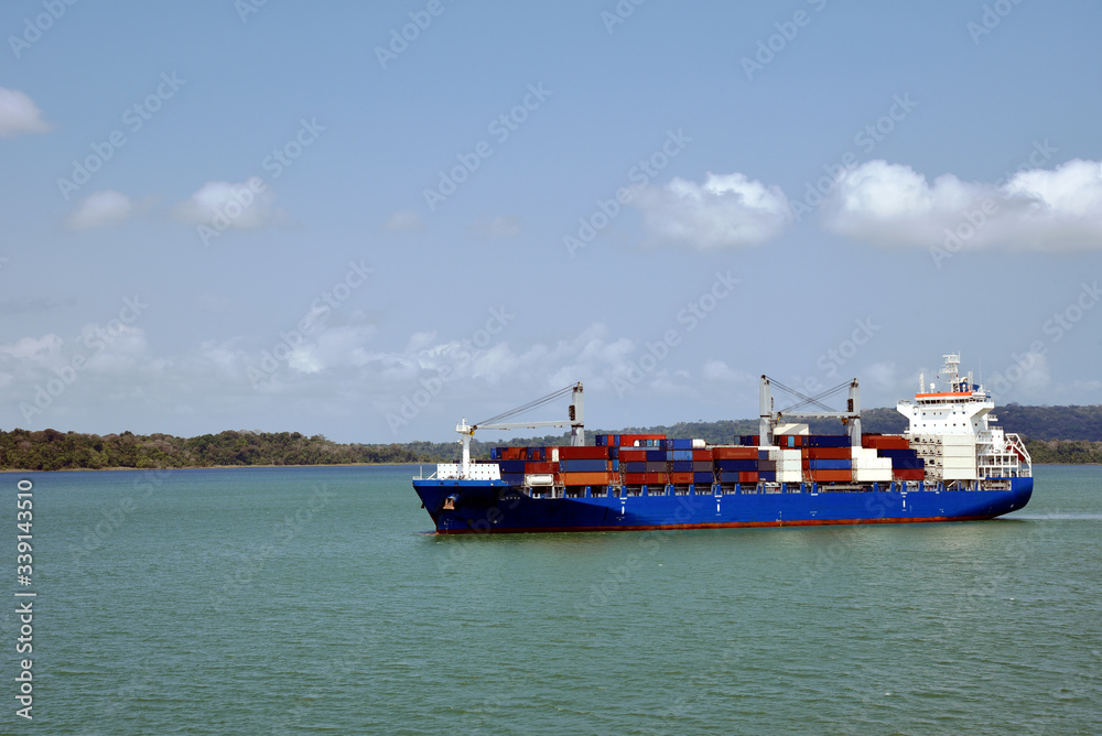 Fototapeta premium Geared container ship transiting through Panama Canal on her international trade route.