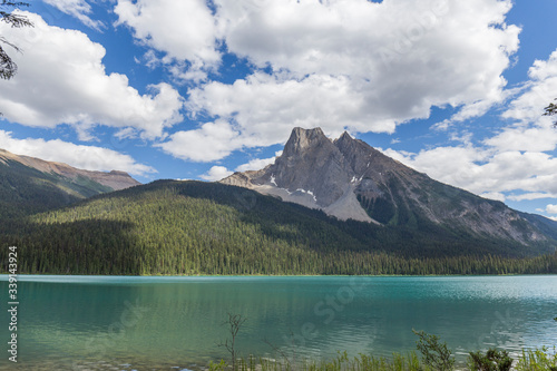 turquoise water lake in the middle of a forest with tall trees and huge mountains  during the summer in Canada