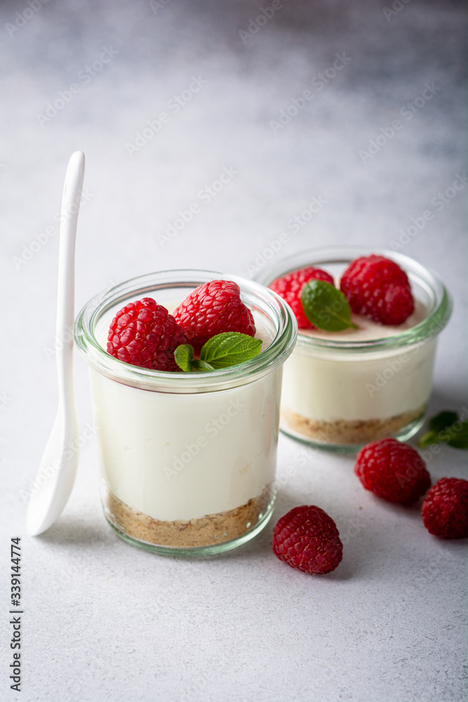 cheesecake in a glass decorated with raspberries and mint on a gray background cheesecake in a glass decorated with raspberries and mint on a gray background