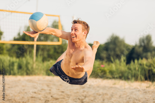 Junger Mann am Hechten beim Beachvolleyball