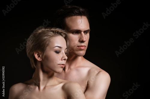 Guy and girl hugging, naked torso on a black background