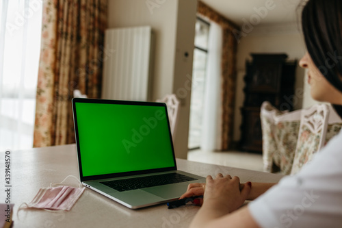 Asian girl using laptop with green screen.