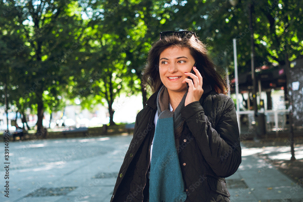Beautiful young businesswoman talking on phone while walking through city Beautiful young businesswoman talking on phone while walking through city