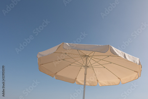 white parasol in front of a sunny blue sky and hot day