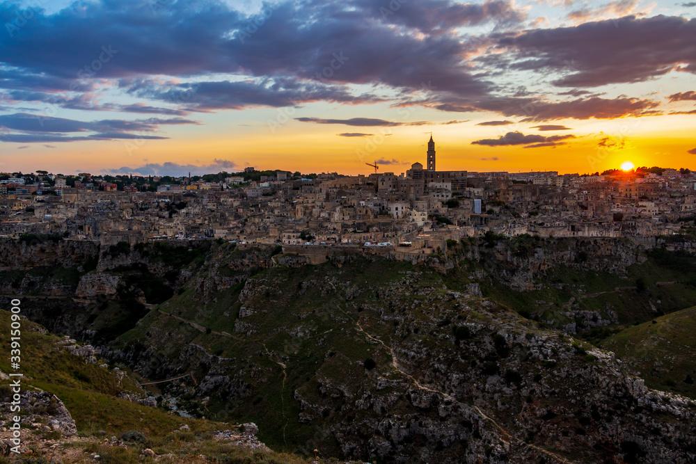 Fototapeta premium Amazing distant sunset panoramic view of Matera from Parco della Murgia Materana or Park of the Rupestrian Churches of Matera in the Province of Matera, Basilicata Region, Italy