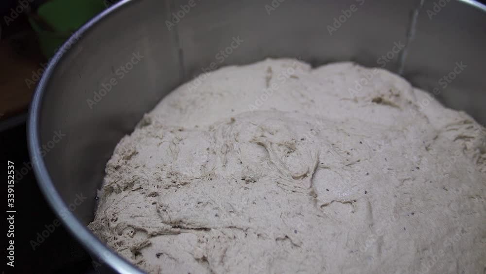 Closeup of kneading dough on kitchen table, side view. Mature woman put sticky dough in flour on table and start kneading it. Closeup of kneading dough on kitchen table, side view. Mature woman put sticky dough in flour on table and start kneading it.