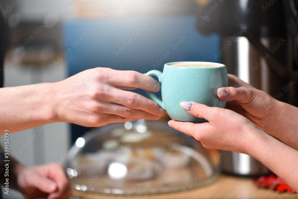 Sale of coffee and hands close-up. The bartender is a barista, has sold a mug of coffee and hands it to the client.