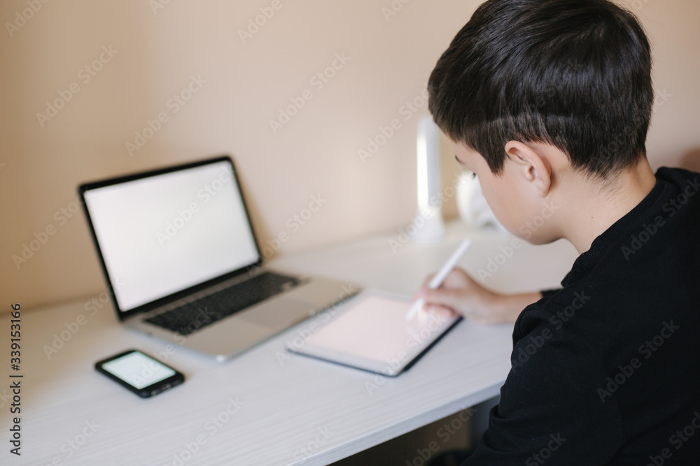 Handsome young boy drawing on tablet at home. Teenage boy use tablet for work. Schoolboy study at home using tablet, laptop, smartphone Handsome young boy drawing on tablet at home. Teenage boy use tablet for work. Schoolboy study at home using tablet, laptop, smartphone