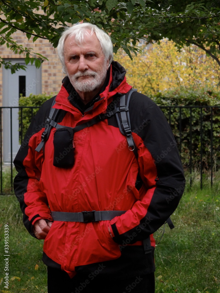 Portrait of a white bearded sprightly senior in red black colored active hiking outfit Portrait of a white bearded sprightly senior in red black colored active hiking outfit