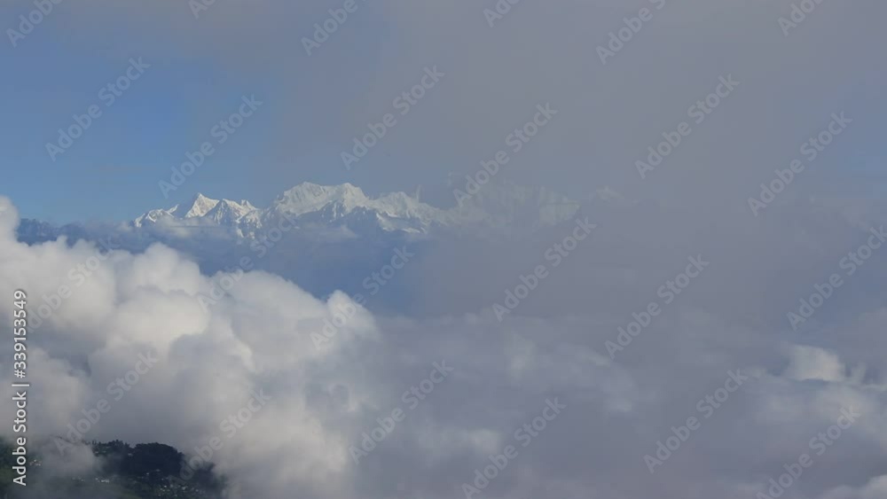 Morning timelapse of full mountain range of kanchenjungha above the clouds which is flowing like a river and constantly changing. Sunny blue clear sky in with blazing white mountain range of himalaya. Morning timelapse of full mountain range of kanchenjungha above the clouds which is flowing like a river and constantly changing. Sunny blue clear sky in with blazing white mountain range of himalaya.