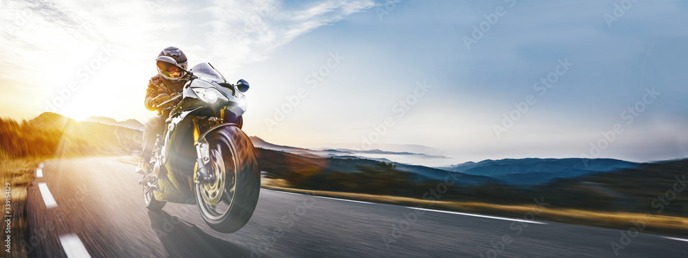 Fototapeta Szybki motocykl na nadmorskiej drodze. dobrze się bawisz jadąc do zachodu słońca