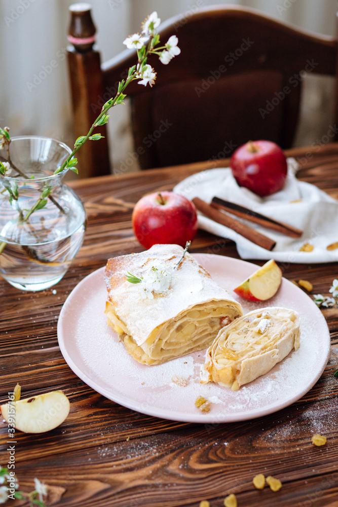 Healthy Home made sweet Apple strudel with raisins and cinnamon on wooden background with blooming fruit branches