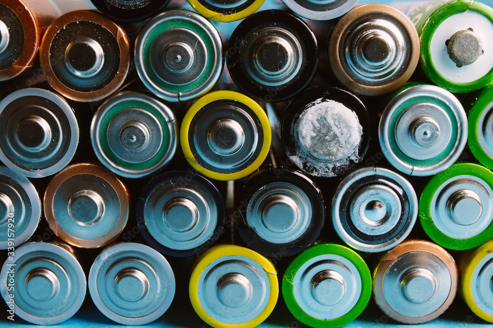 Old used AA-size lithium-ion batteries lie on top of each other, one battery is leaking Old used AA-size lithium-ion batteries lie on top of each other, one battery is leaking