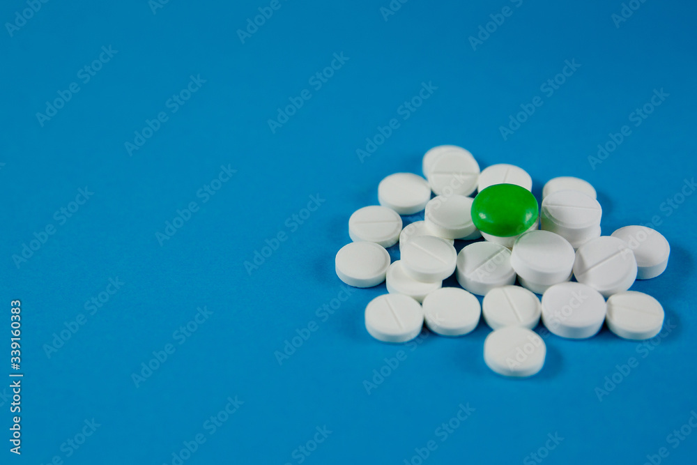 A slide of white and green pills lie on a blue monophonic background