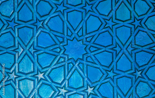 Blue wooden background. element o wooden surface with carved oriental patterns, stars, circles, triangles is tinted in light blue, turquoise color. Place for text. Copy space. Selective focus.