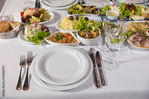 Salads and gums . Set of a dish with spoon, fork and knife on white table.Table setting on white table .
