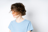 Happy beautiful young girl in a blue T-shirt shakes her head with her haircut on a white background
