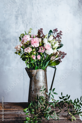 bouquet of pink and white flowers in metal jug on wooden table